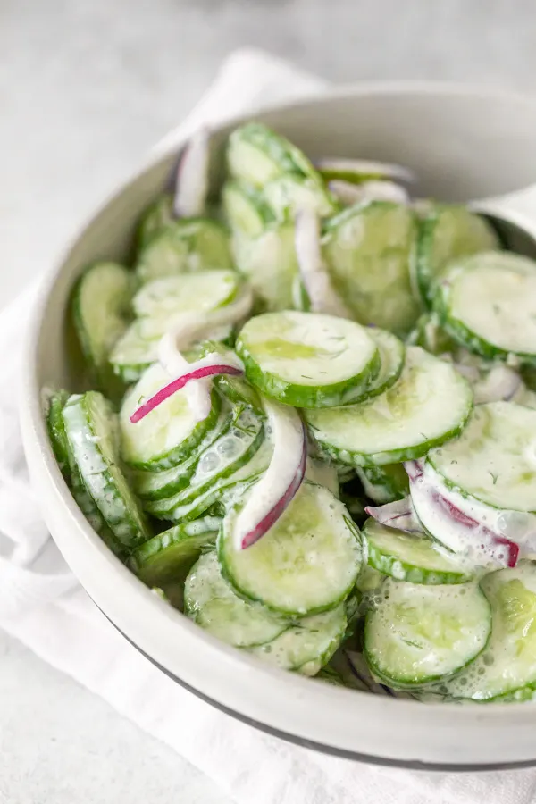 creamy horseradish cucumber salad served in a bowl sitting on a napkin. 