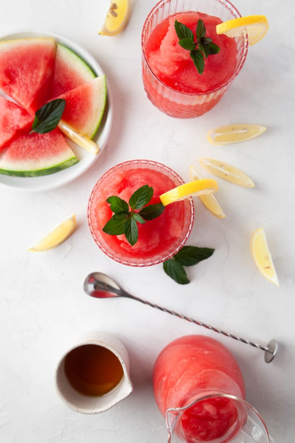 Watermelon Frose sitting in a glass served with fresh watermelon slices. 
