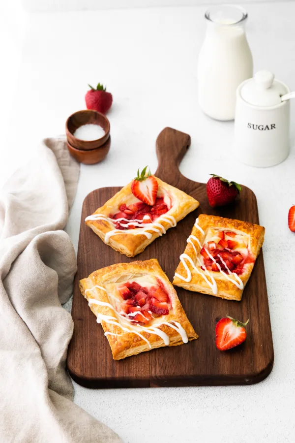 easy strawberry cheesecake Danish served on a cutting board with fresh berries. 