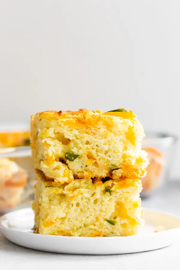 2 pieces of jalapeño cheddar cornbread stacked on a plate. 