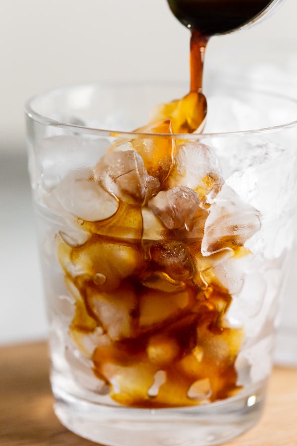 Apple brown sugar molasses coffee syrup being poured over ice in a glass. 