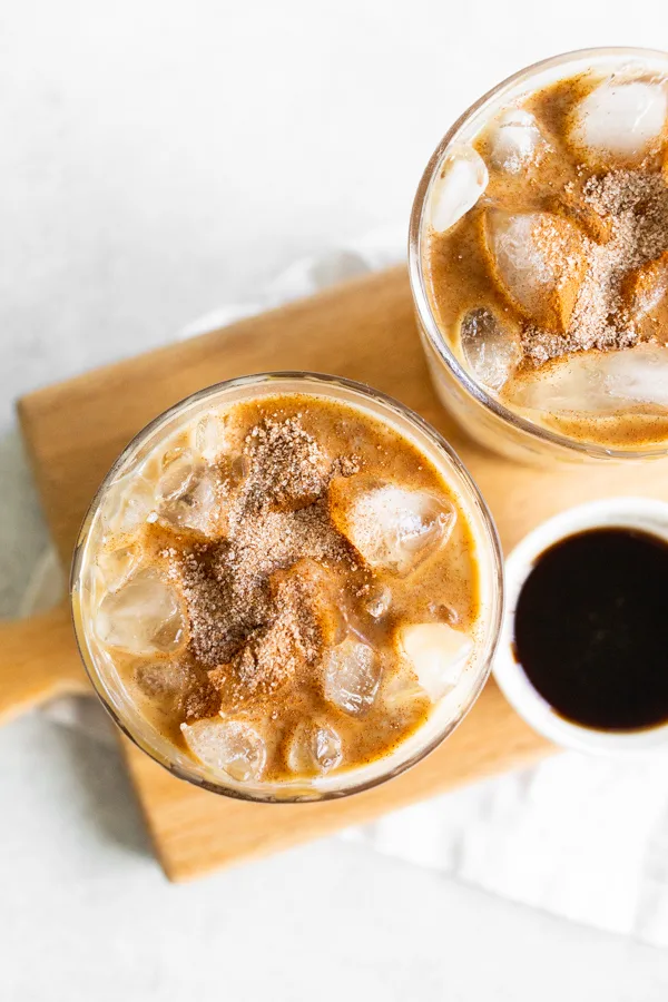 Apple Crisp Macchiato in a glass with ice and topped with cinnamon sugar and caramel drizzle. 