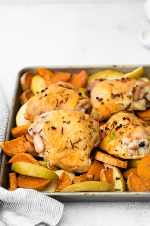 Sheet Pan Chicken and Apples on a sheet pan sprinkled with rosemary. 