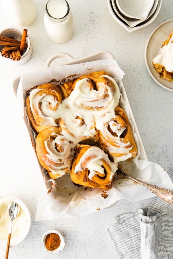 Gingerbread Cinnamon Rolls served on a table with extra icing. 
