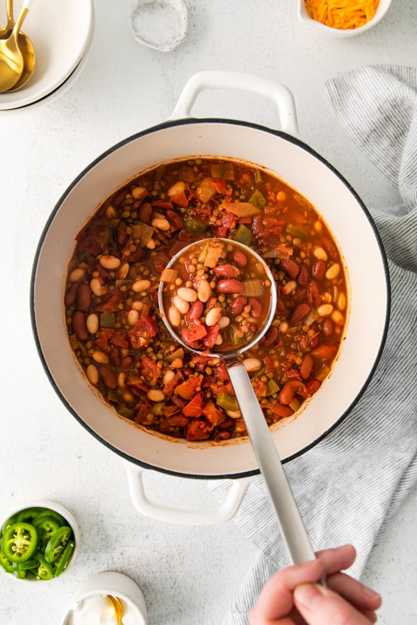 Vegan Lentil Chili being scooped out of a dutch oven soup pot. 