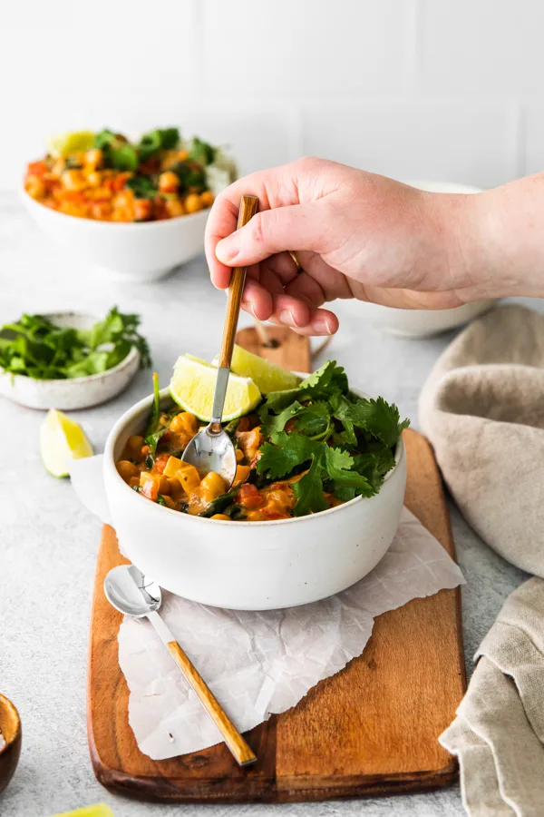 A hand taking a bite of Vegan Chickpea Curry out of the bowl. 