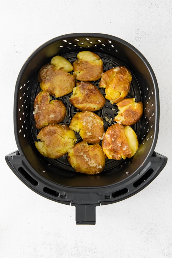 smashed potatoes in an air fryer basket. 