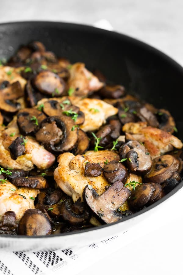 Garlic Mushroom Chicken Thighs in a pan with fresh herbs. 