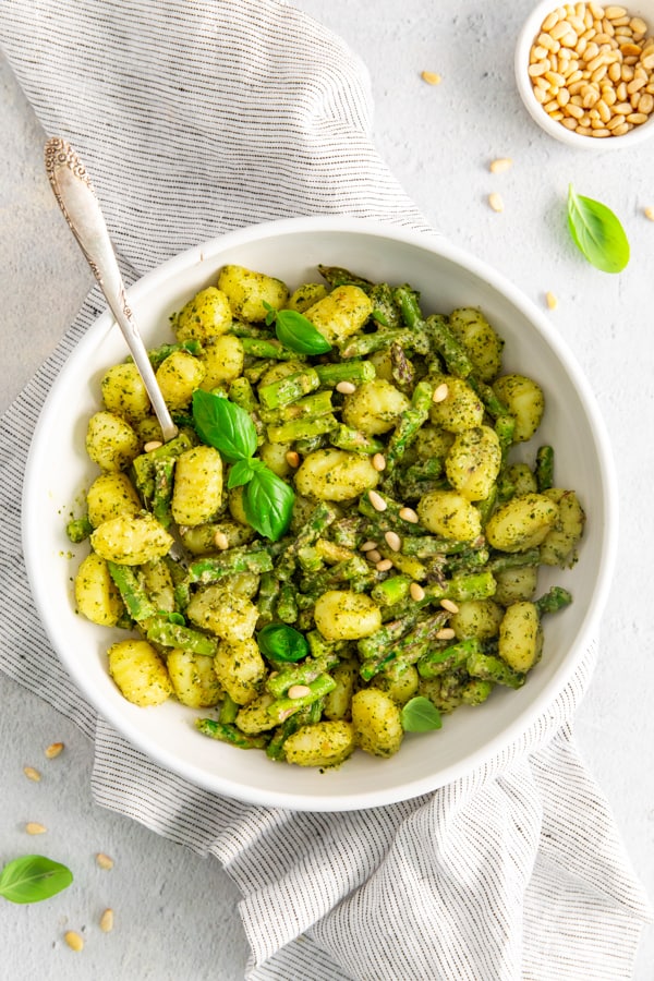 Pesto Gnocchi with Asparagus in a bowl topped with pine nuts.