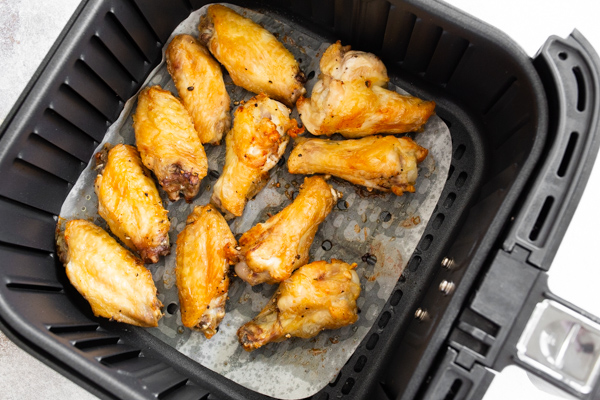 air fryer chicken wings in the basked of the air fryer. 