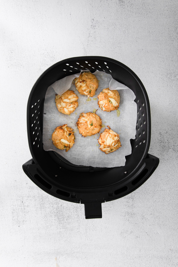 Air Fryer Crab Cakes sitting in an air fryer basket. 