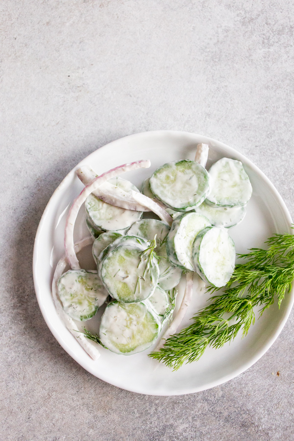 Creamy Cucumber Salad served on a plate with fresh dill. 
