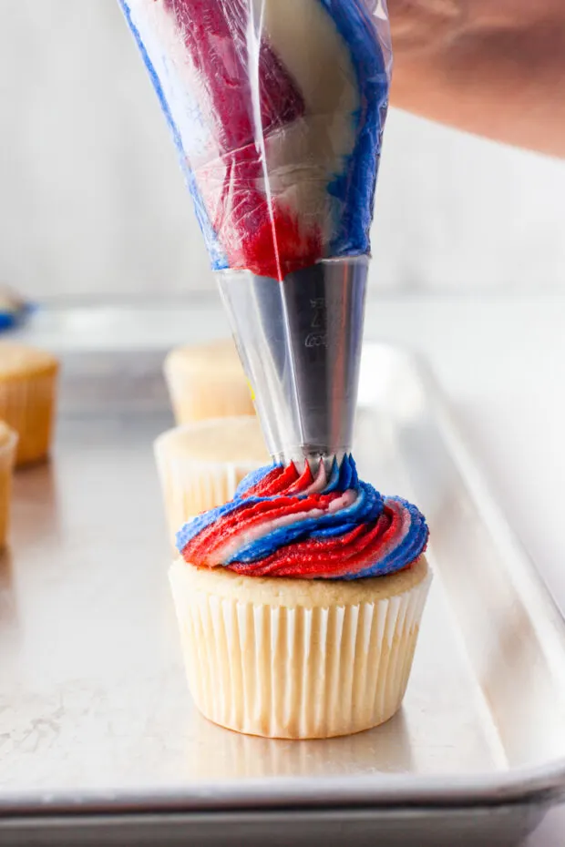 Frosting getting piped onto Fourth of July Cupcakes. 