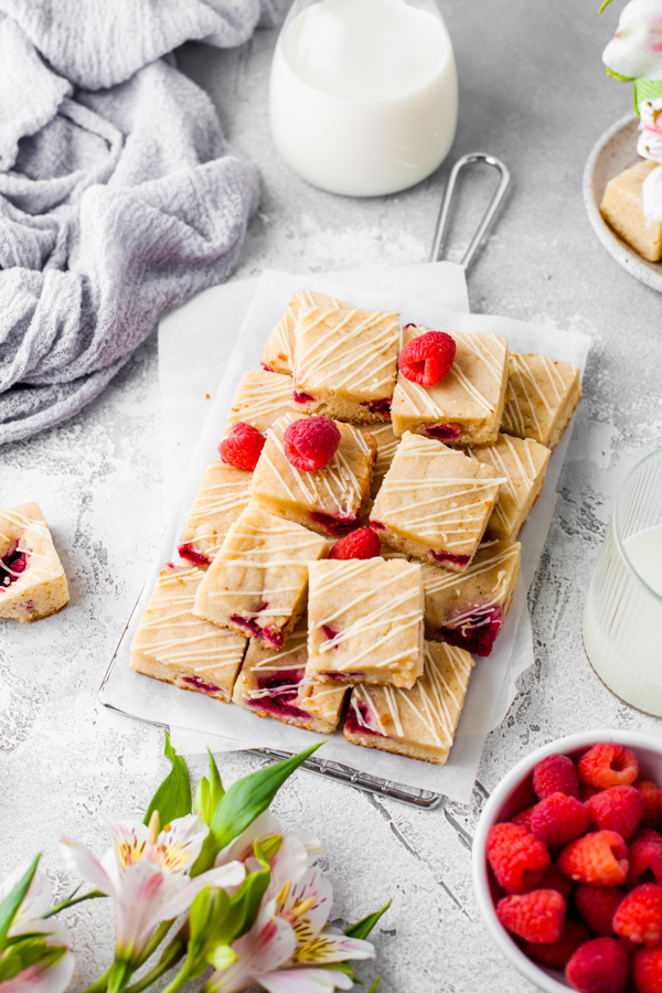 White chocolate raspberry blondies on a table cut and stacked. 
