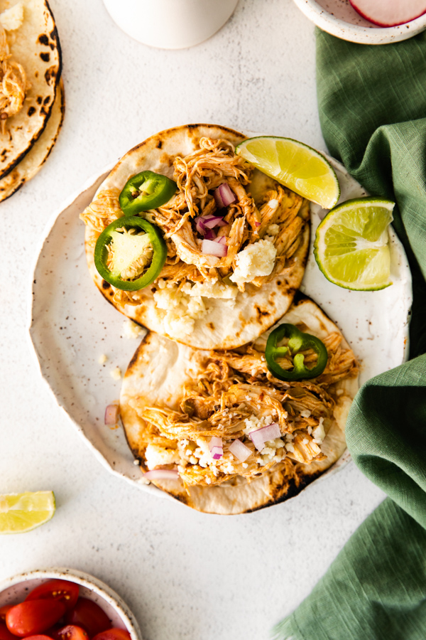 Instant Pot Pulled Chicken Tacos on a plate with lime and jalapeno. 
