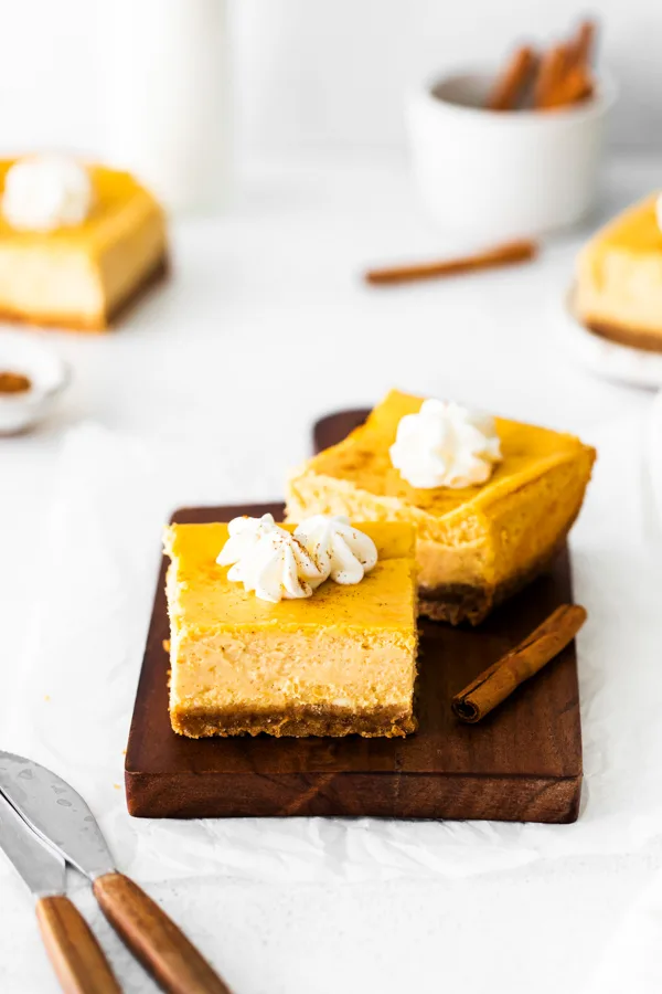 Cut pumpkin cheesecake bars topped with whipped cream. 