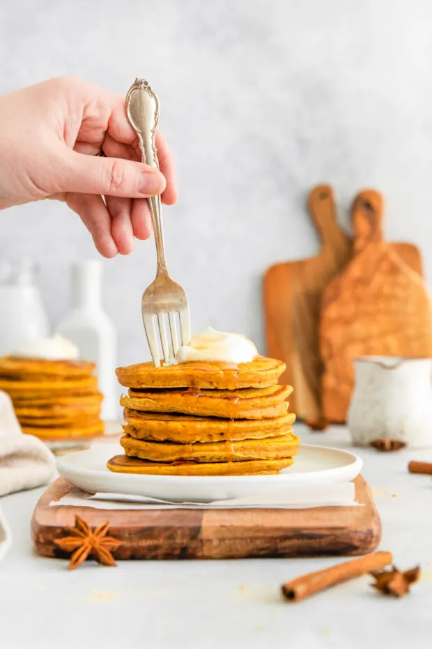 A fork going into a stack of pumpkin pancakes. 