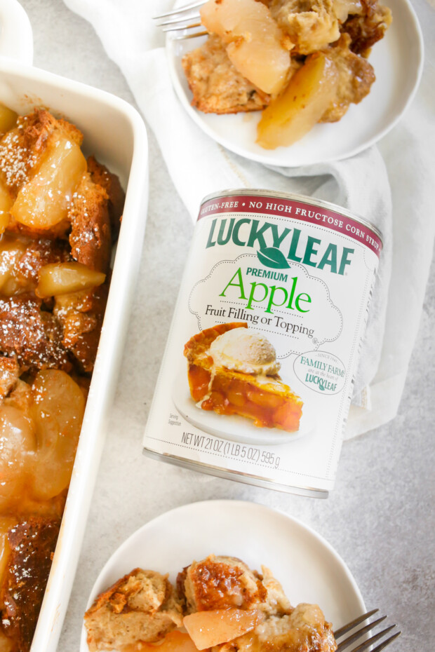 A can of apple pie filling sitting on a table between 2 plates of Apple Pie Baked French Toast. 