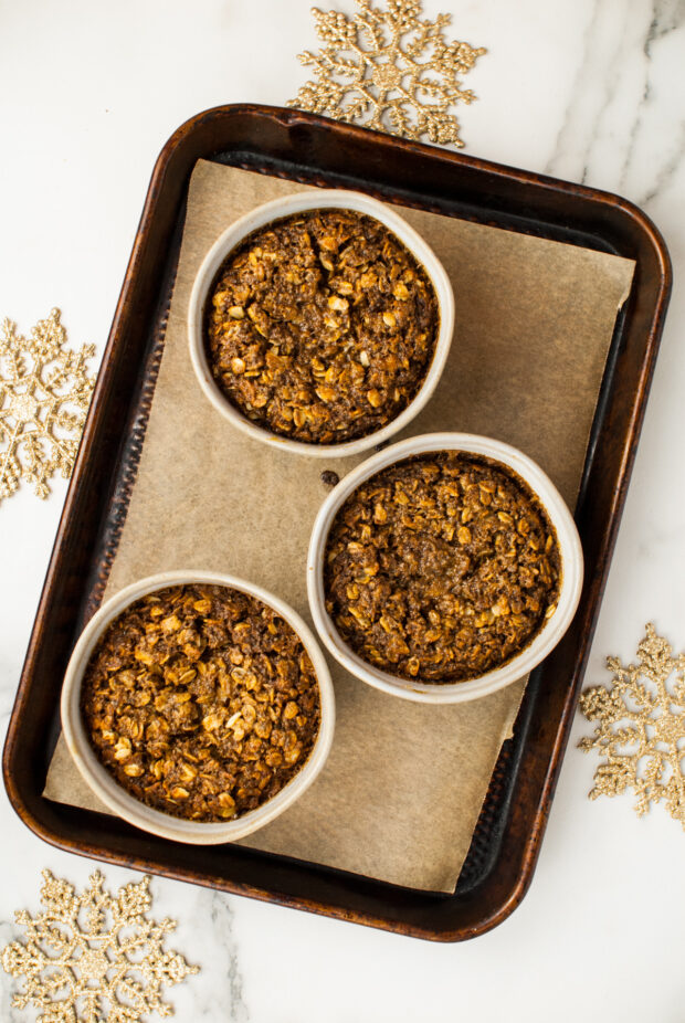 Baked Gingerbread Oatmeal baked in bowls sitting on a sheet pan. 
