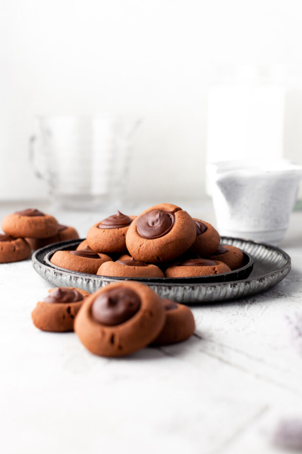 Double Chocolate Thumbprint Cookies sitting on a plate with milk. 
