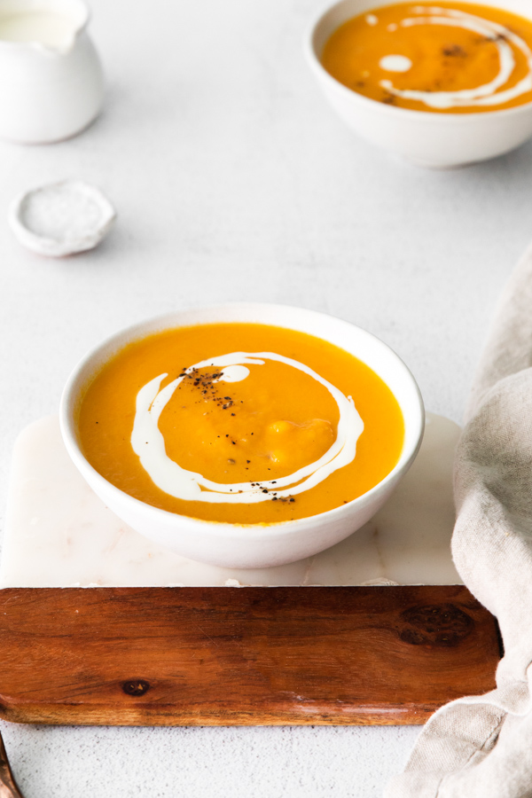 Instant Pot Butternut Squash Soup in a bowl with cream drizzled on top. 