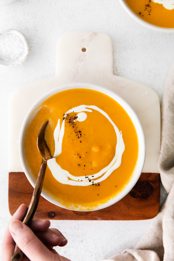 A spoon taking a spoonful of Instant Pot Butternut Squash Soup out of a bowl. 
