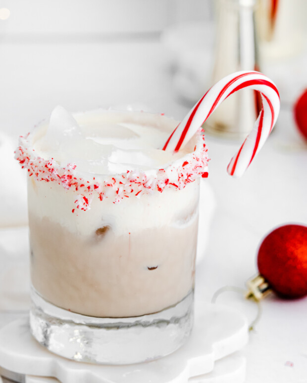 Peppermint White Russian in a glass with a candy cane. 