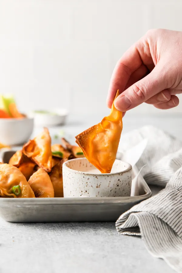 Air Fryer Buffalo Chicken Wontons being dipped into blue cheese dressing. 