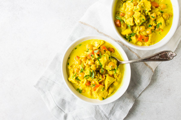 Chicken Coconut Milk Turmeric Soup in a bowl with a spoon. 