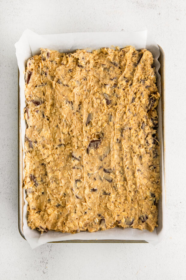 Chocolate Chunk Oatmeal Cookie Bars uncooked in a quarter sheet pan. 