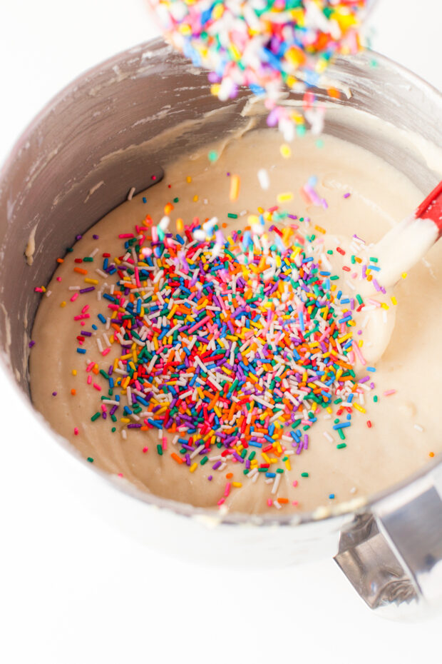 Sprinkles getting poured into cake batter. 