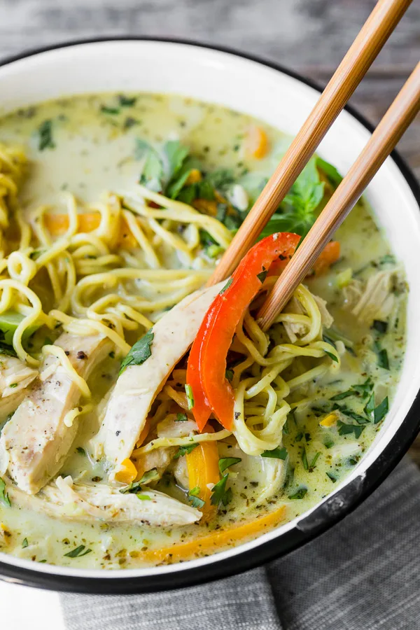 Green Curry Chicken Noodle Soup with a pair of chopsticks in the soup bowl. 