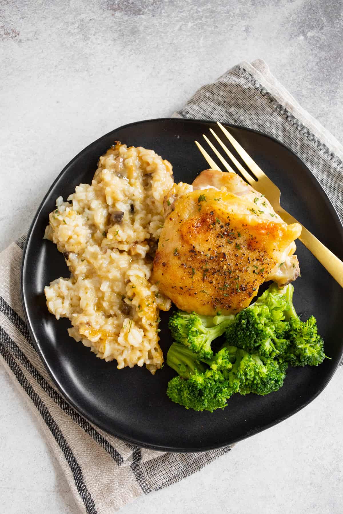 Effortless Chicken and Rice Bake 9 A single serving of Easy Chicken and Rice Casserole on a black plate, with a fork, ready to eat.