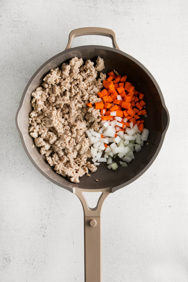 Ground chicken and vegetables in a skillet. 