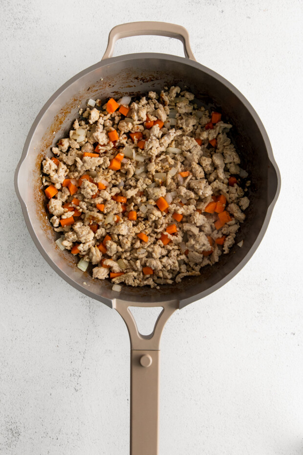 ground chicken and vegetables mixed together in a skillet. 