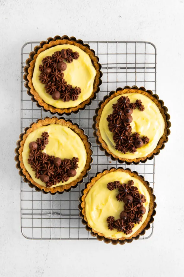 Boston Cream Pie Tarts cooling on a rack. 