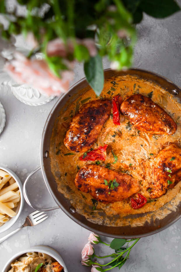 Creamy Tuscan Chicken in a skillet on a table. 