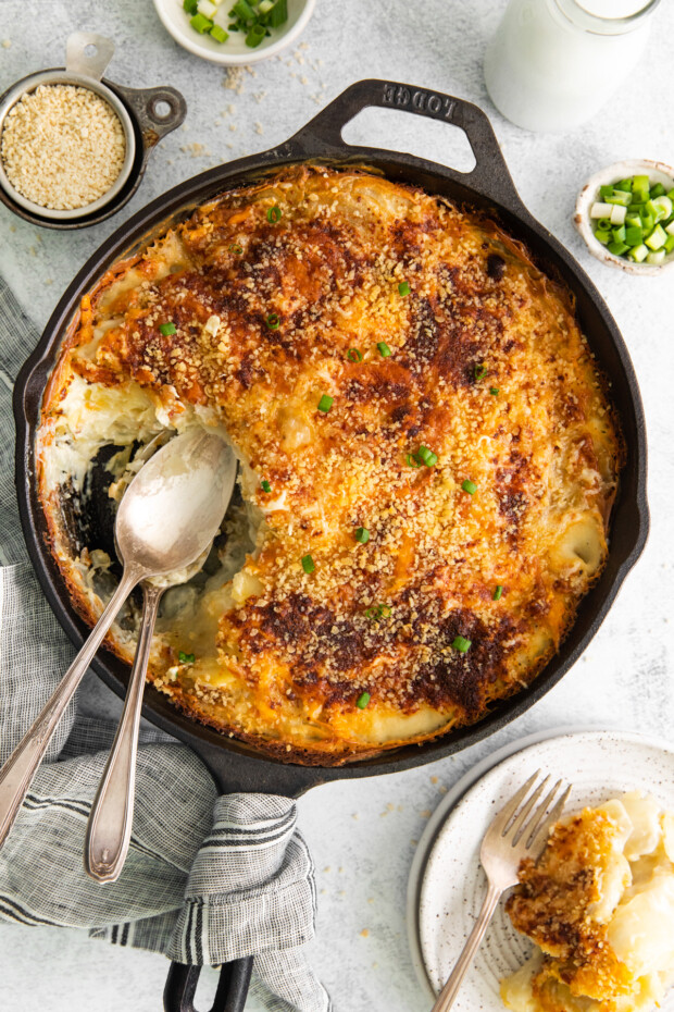 Homemade Scalloped Potatoes in a skillet with serving spoons. 
