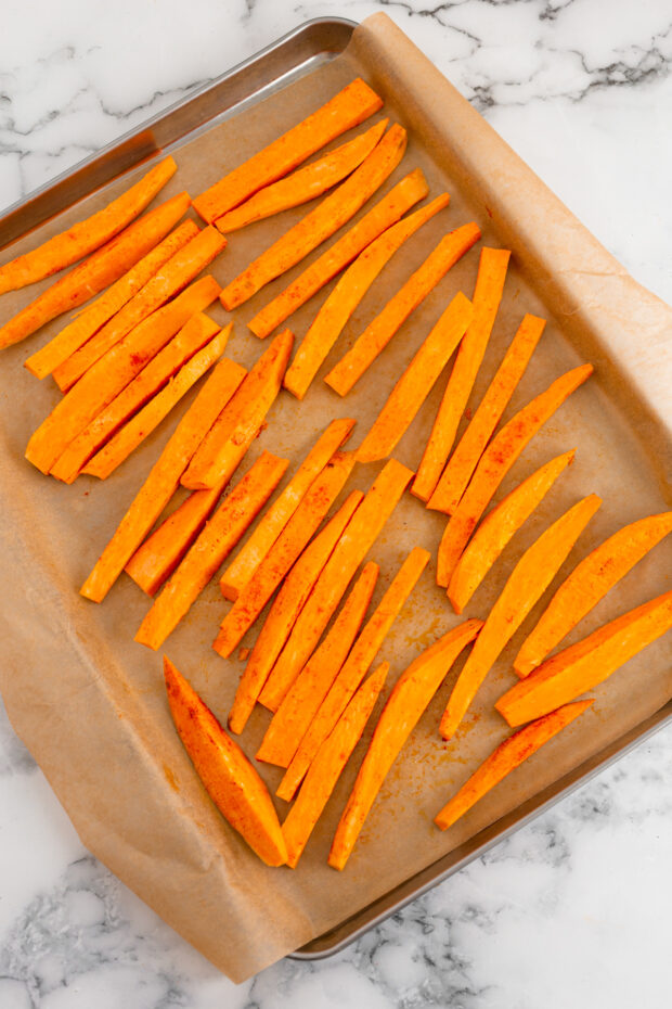 Uncooked sweet potato fries on a sheet pan. 