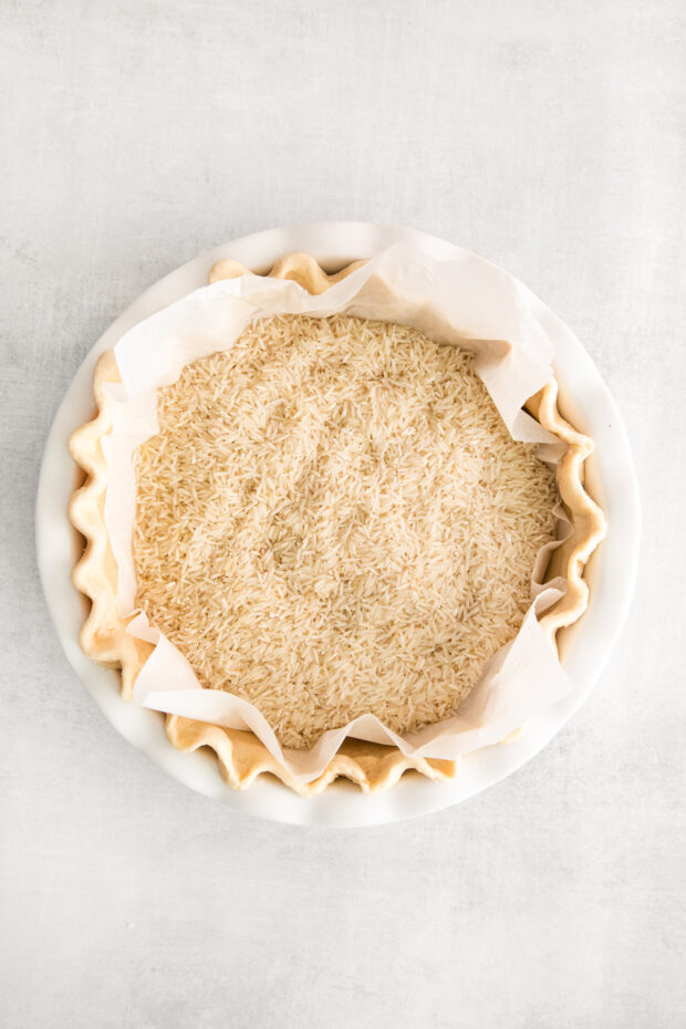 An uncooked pie crust with parchment paper in it with rice to help  weight it down. 