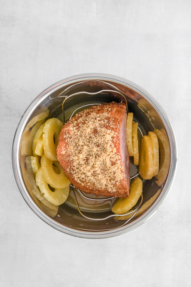 A ham sprinkled with brown sugar and ham inside an Instant Pot. 