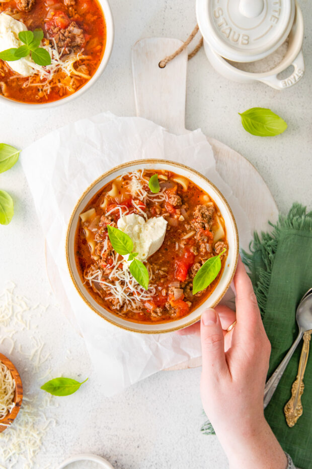 Instant Pot Lasagna Soup n a bowl with a hand holding the bowl. 