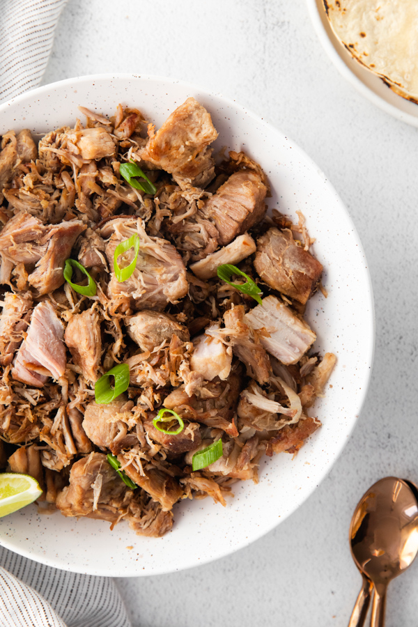 Slow Cooker Pork Carnitas in a bowl topped with green onions. 