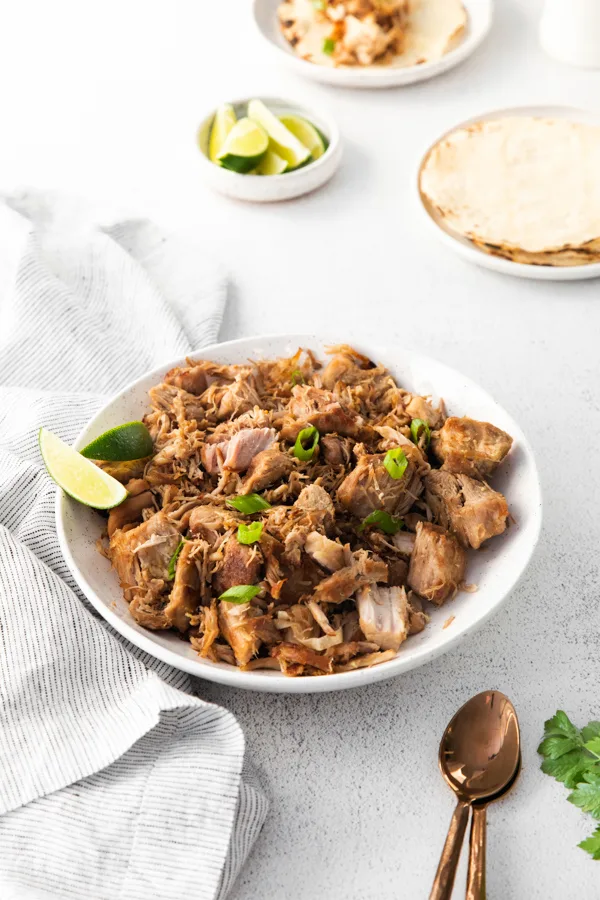Slow Cooker Pork Carnitas on a plate with a tortilla. 