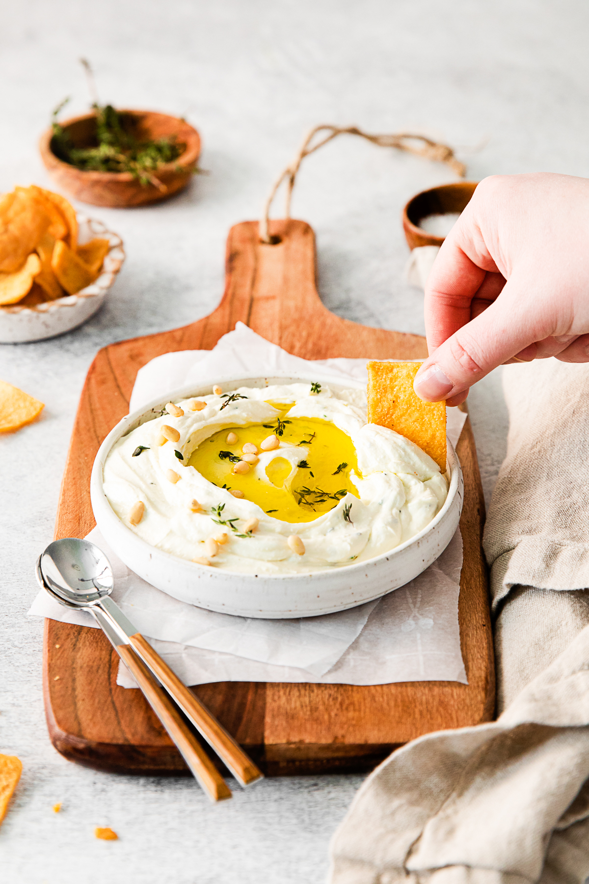 A hand dipping into Roasted Garlic Whipped Feta. 