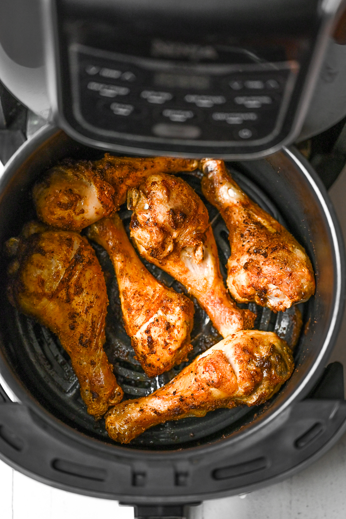 Air Fryer Chicken Legs just cooked sitting in the air fryer basket. 