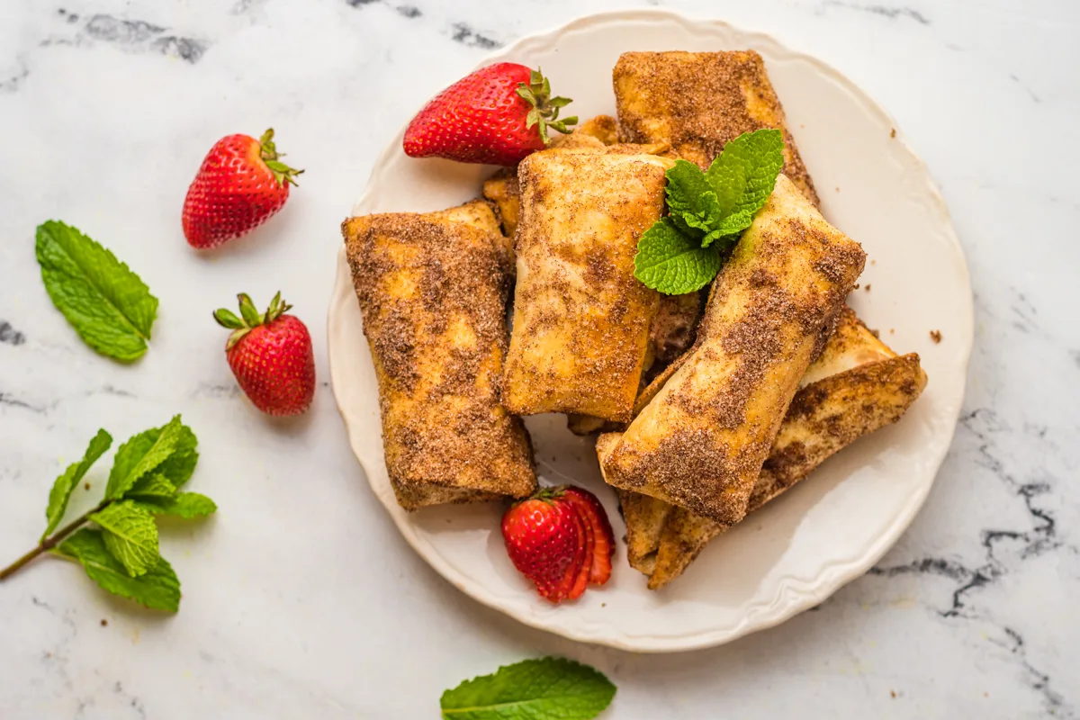 Air Fryer Strawberry Cheesecake Chimichangas served with fresh berries. 