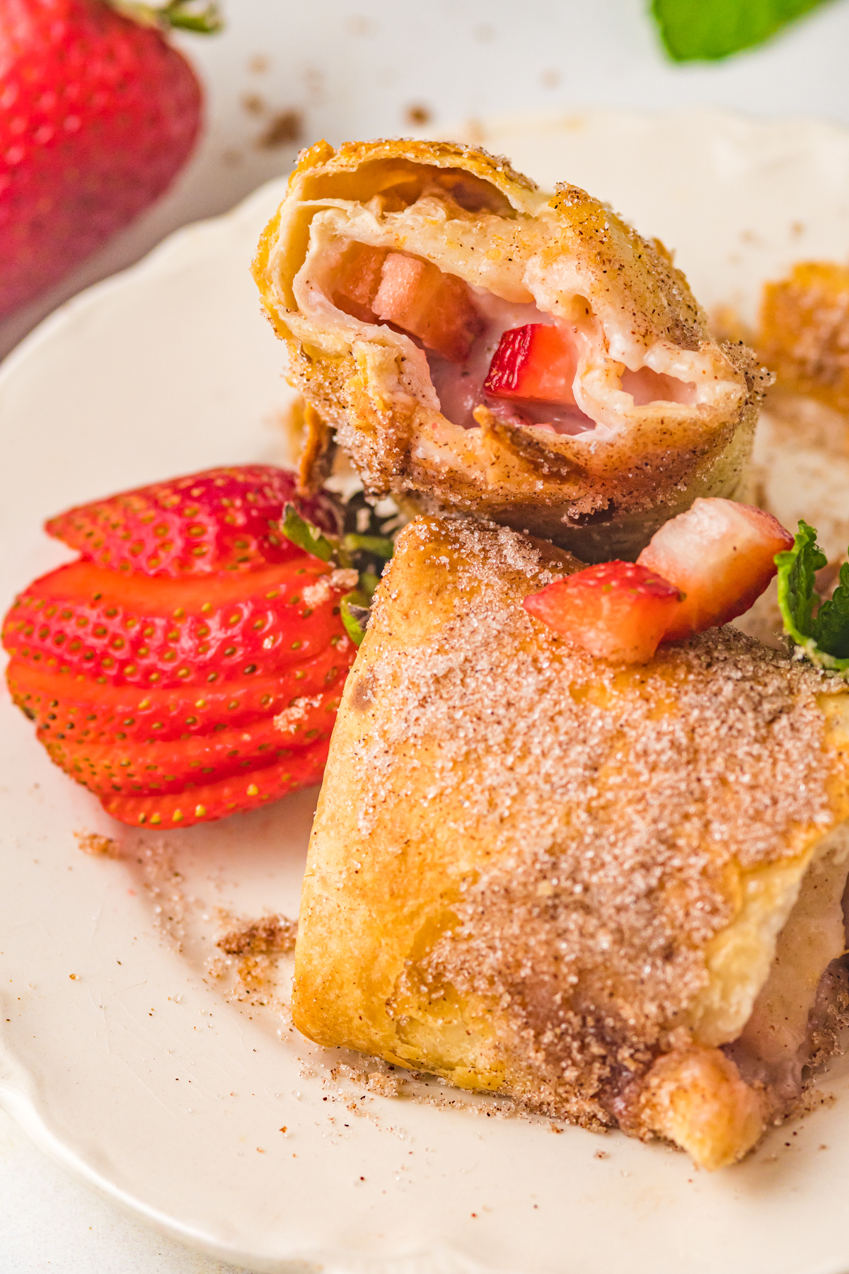 Air Fryer Strawberry Cheesecake Chimichangas served with mint leaves and strawberries. 