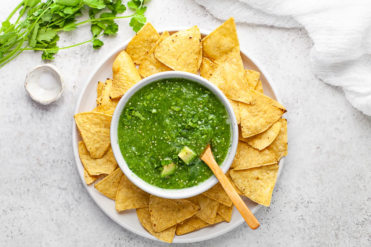 Homemade Salsa Verde in a bowl with chips and extra cilantro on top. 