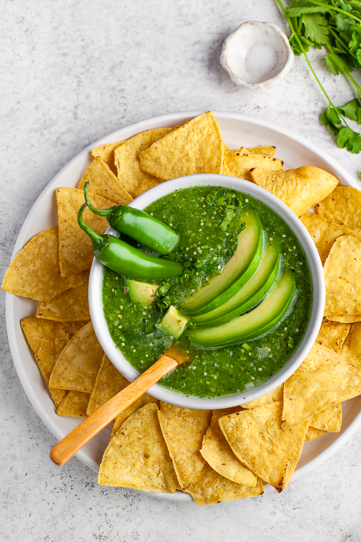 Homemade Salsa Verde on a plate surrounded by corn tortilla chips. 
